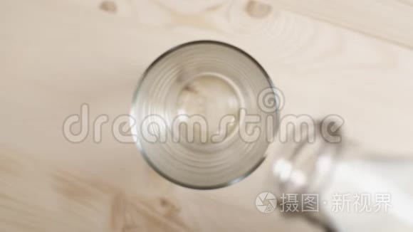 把牛奶倒在木桌上的玻璃杯里，把从透明瓶子里倒出来的牛奶合上