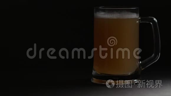 明亮的大玻璃杯与冷啤酒周围的聚光灯隔离在黑色背景