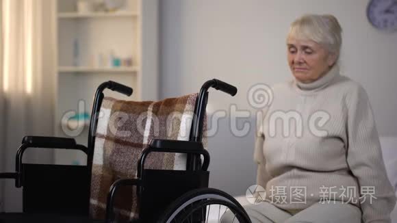在康复中心坐在轮椅旁的沙发上，心烦意乱的老年妇女