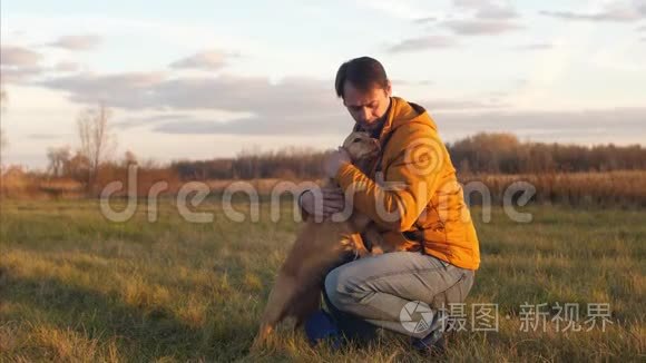 男人正在抚摸他最喜欢的红狗头上，微笑着在公园散步