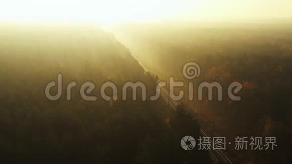 黎明时分，一架无人机在雾蒙蒙的铁路上缓慢飞行，穿过秋天的森林。