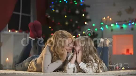 年轻的女人和女孩在圣诞树下抚摸，微笑着对着镜头，节日