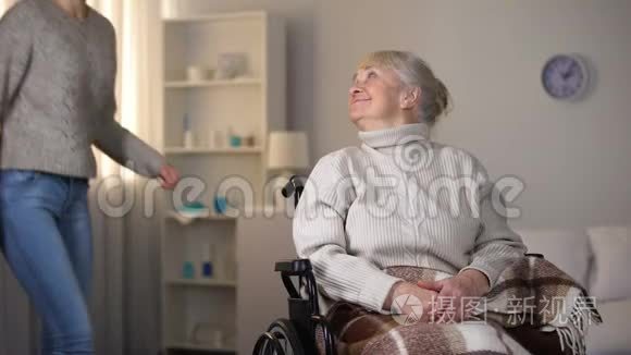 孙女拥抱轮椅上微笑的老妇人，家人的爱和关怀