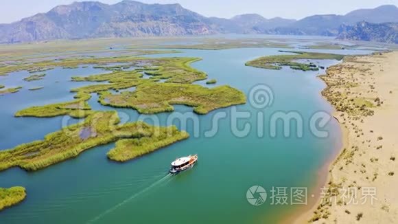 摩托艇漂在河上，旁边是沙岸.. 达兰河和伊兹图祖河。 背景中的山脉