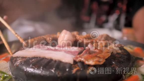 人们用筷子做饭捡猪肉翻猪肉，在火锅上用深色和谷物的方法迎接韩国烧烤