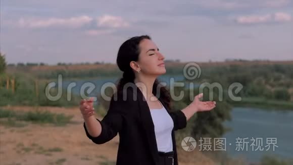 年轻的商务女性看着夕阳的天空，成功的女孩思考着大自然中的生活，享受着