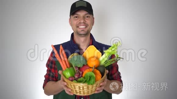微笑的农夫手里拿着一篮子新鲜的有机水果和天然蔬菜