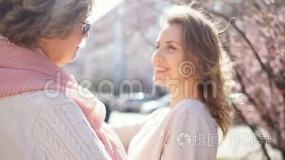 年轻漂亮的女儿抱着成熟的母亲，站在罗戈德街的中间，背景是