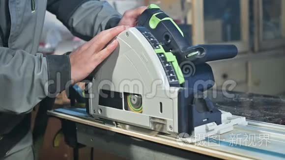 木工`在家庭车间用手圆锯加工的手的特写。 整理木制部件