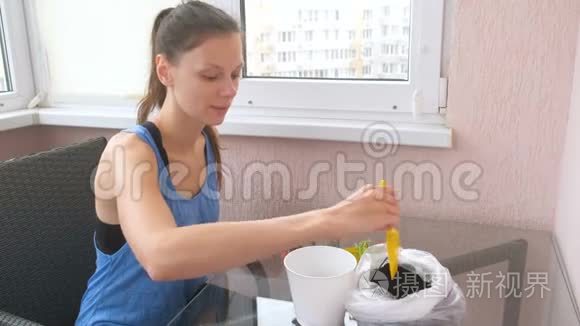 植物护理理念。 女人在种房子。 用一个小小的炫耀把地球移到一个罐子里。 侧视。