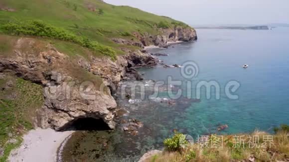 美丽的夏日海景。 美丽的风景，岩石海岸的绿松石海和绿草。