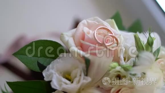 白色玫瑰上金色结婚戒指的特写。