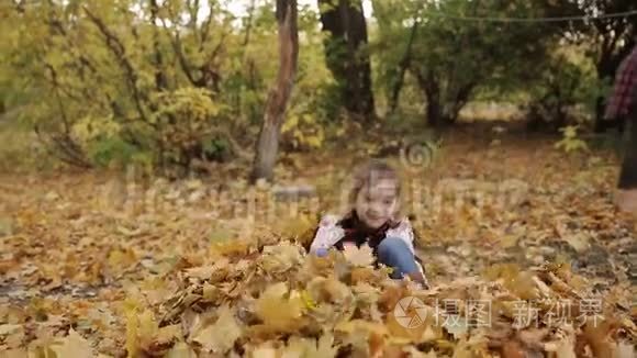 这个淘气的小女孩在一大堆黄色的叶子里快乐地玩耍。 女孩把黄叶扔上去。