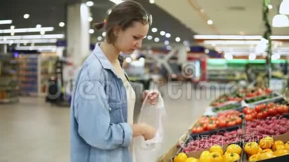 购物。 女人在蔬菜商店或超市选择生物食品黄色番茄。 一个接一个地把它放进