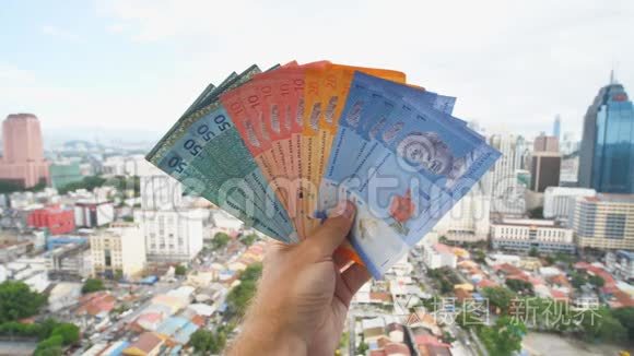 一个年轻人拿着马来西亚的钱在吉隆坡市中心的背景下。