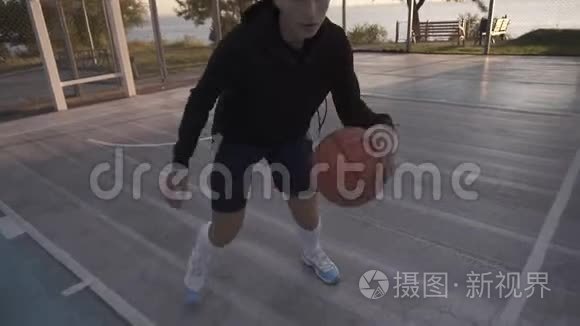 女篮球运动员在晨光职业球场与球一起跑步。 手持录像。 关门