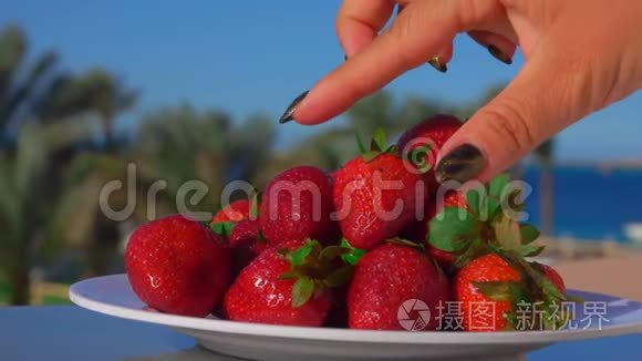 女人的手从盘子里拿出一个大草莓