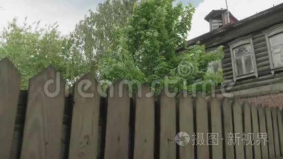 俄罗斯旧的有栅栏的木制房子，旁边是绿树
