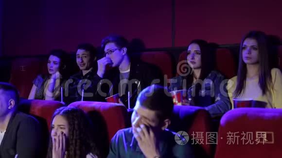 一群年轻人在电影院看一部悲伤的电影，女孩在哭。