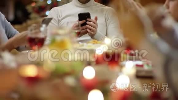 家庭成员在圣诞餐桌旁使用智能手机，每个人手上都有手机