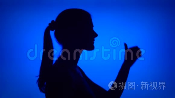 女人的剪影在蓝色背景上构成拇指。 女`的脸在侧写显示竖起大拇指