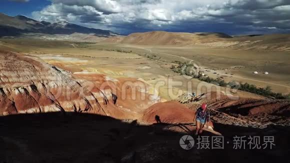 年轻的旅游妇女在阳光明媚的日子里爬上一座红石山。 这里风景秀丽，天空阴云密布