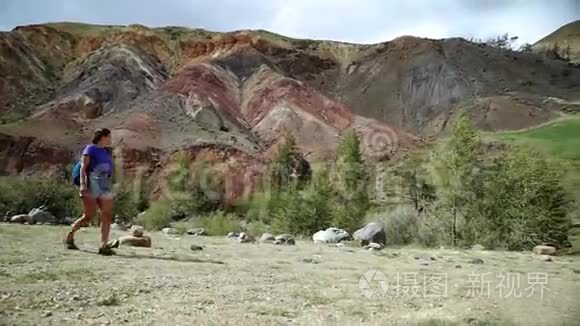 年轻的旅游徒步旅行者正沿着一座红色的石山散步