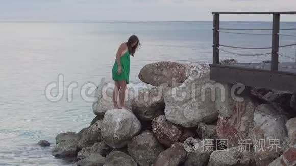一个女人站在海边的岩石上