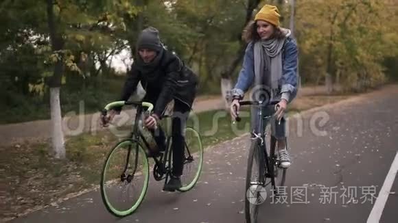 快乐的，微笑的朋友或年轻的夫妇骑着自行车在秋天的公园骑自行车。 男子和妇女