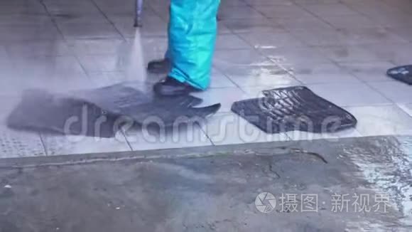 一个工人在水压下为汽车洗垫子