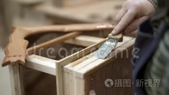 男性手刮木巢箱底部的硬胶