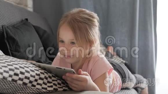 十几岁的女孩玩平板电脑，躺在家里的沙发上。 人，技术和休闲理念..