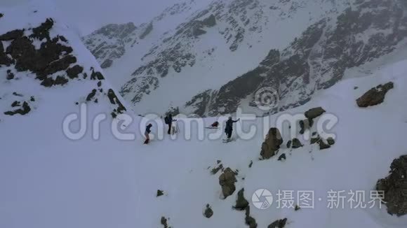 雪灾期间，三名滑雪者站在一座山峰上的美丽空中镜头，4k