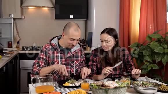 夫妻俩坐在餐桌旁的厨房里吃午饭。 桌子上有沙拉、蔬菜、蔬菜