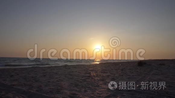 两个年轻的女人正沿着一片荒芜的海滩朝大海上的夕阳跑去