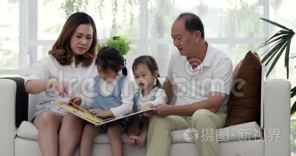 父亲、母亲和小女儿在客厅的沙发上读`本孩子的书。