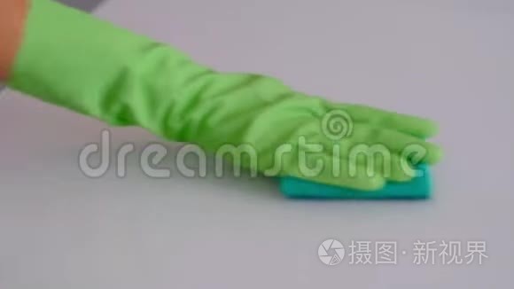 慢动作。 用绿色橡胶手套把一只家庭主妇的手合起来，用清洁剂擦拭桌子上的污垢