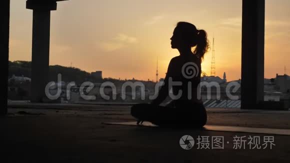 Yogi女孩坐在莲花的姿势下，在日落时分，在夏天废弃的建筑物里改变它，健康的生活方式，运动