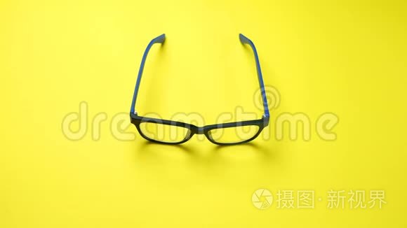 人类双手搜索，在蓝色塑料框架中找到并拿走眼镜。 在黄色背景上。