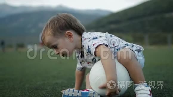 小男孩带球坐在足球场上视频