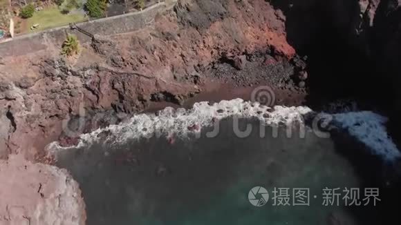 空中射击。 岩石火山岸，蓝色的海浪在上面拍打。 在陆上设施和