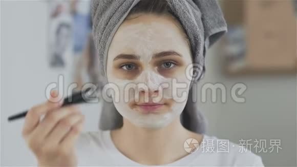头上戴毛巾的女人戴上化妆面具看着镜头
