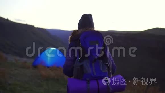 日落时分，背着徒步旅行背包的女人回到了帐篷