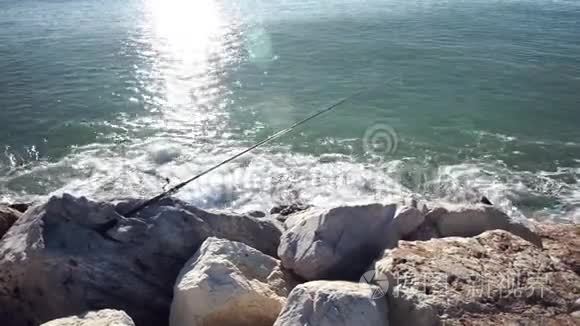 钓鱼竿躺在岩石海岸上视频