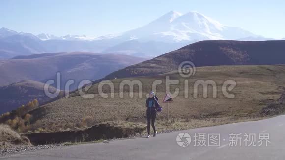 年轻的阿拉伯女人带着旅游背包和太阳镜在风景如画的山路上旅行，慢悠悠