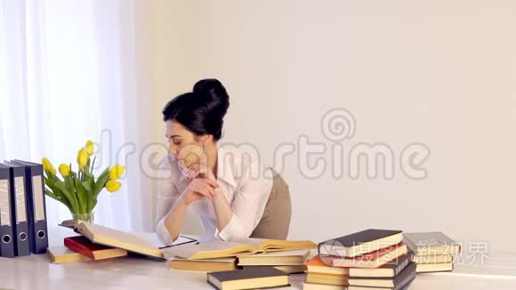 工作太累了，困倦的年轻女人坐在书桌前拿书