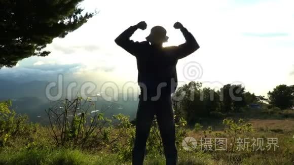 到达顶峰。 人在日出时跳得开心，在美丽的山峦上举手。 感觉不错