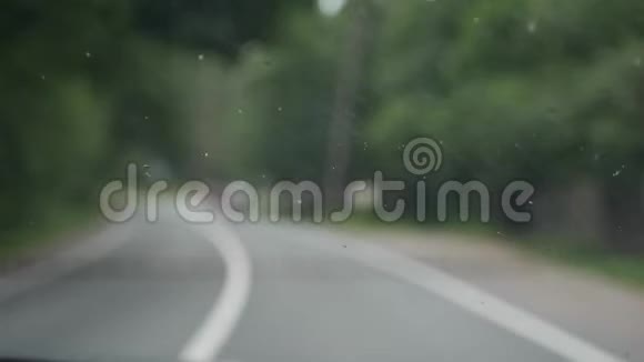 毒蛇清理汽车上的挡风玻璃。 在模糊的乡间道路上。 4k视频的预览图