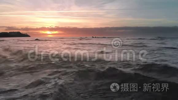 空中射击。 海面上的日出和岛上的火山海滩。 海浪和太阳出现在地平线上