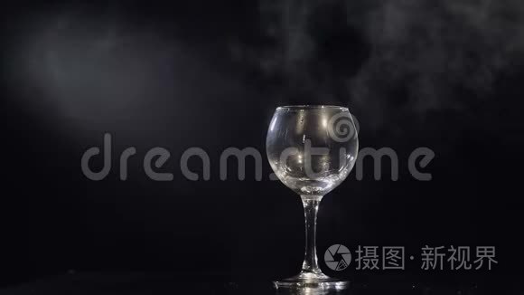 把粉红色的香槟从瓶子里倒入玻璃杯里。 黑色背景。 慢动作